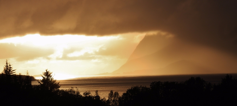 Solnedgang med lysstråler gjennom skyene over Senja